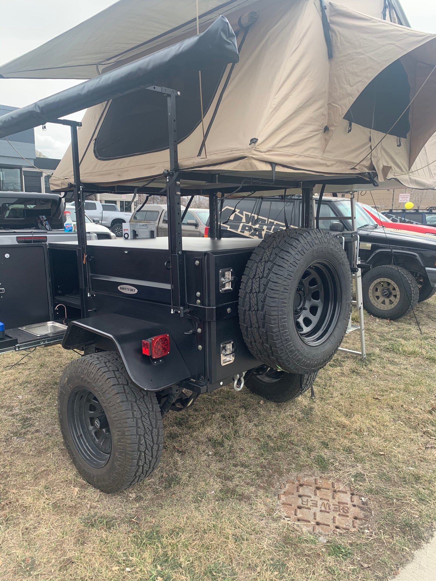 Explore off-grid with this rugged overland trailer, featuring a rooftop tent and integrated kitchen. Ideal for specialized RV rental adventures.