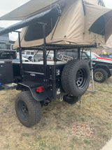 Explore off-grid with this rugged overland trailer, featuring a rooftop tent and integrated kitchen. Ideal for specialized RV rental adventures.