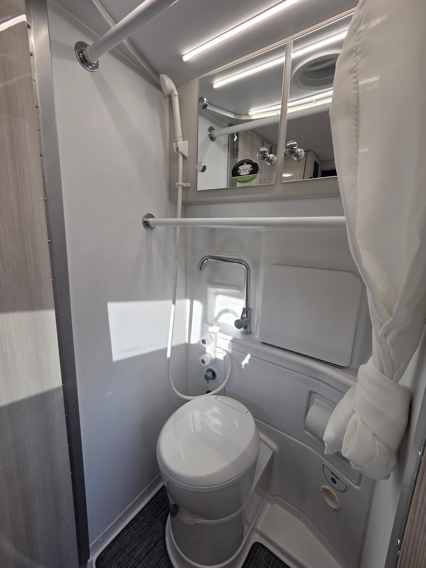 Compact and functional RV rental bathroom, featuring a toilet, shower, and mirrored cabinet for convenient travel. — photo 8