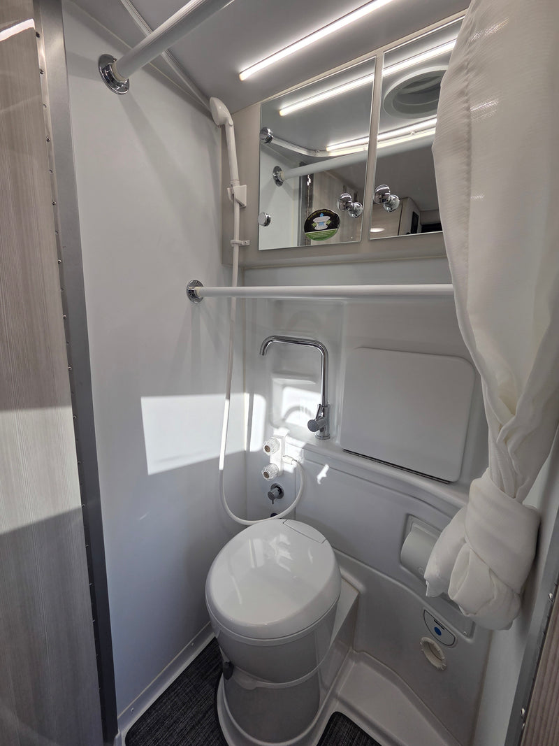 Compact and functional RV rental bathroom, featuring a toilet, shower, and mirrored cabinet for convenient travel. — photo 8