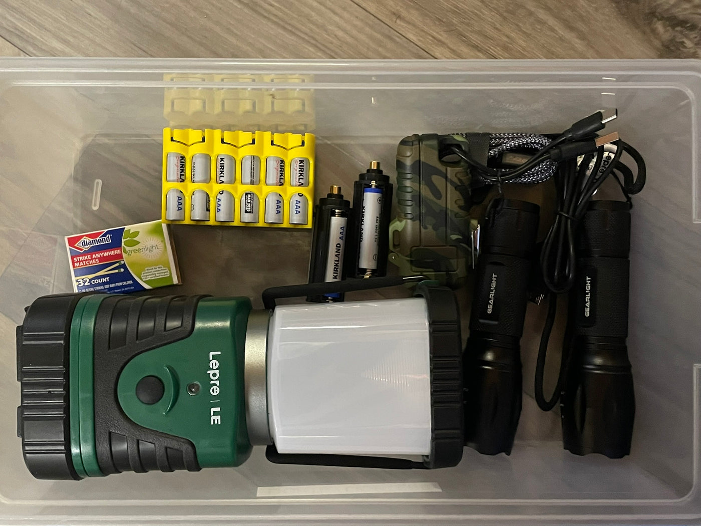 RV rental ready: Clear bin with camping essentials like batteries, flashlights, a trail camera, and matches. — photo 15
