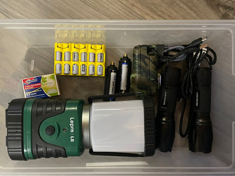 RV rental ready: Clear bin with camping essentials like batteries, flashlights, a trail camera, and matches.