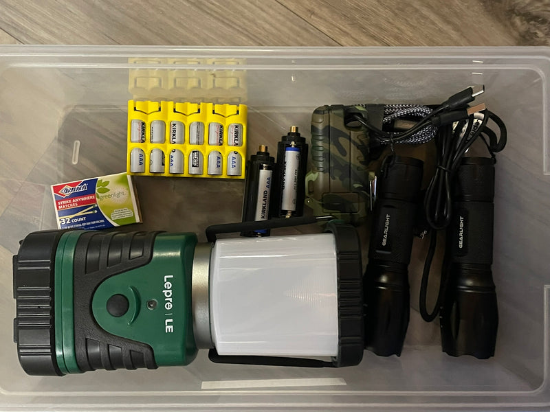 RV rental ready: Clear bin with camping essentials like batteries, flashlights, a trail camera, and matches. — photo 15