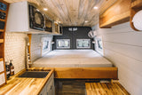 RV rental interior: A cozy camper van with a spacious bed, modern kitchen, and wooden accents throughout.