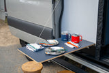 Enjoy outdoor dining from your **rv rental** van! Ret retractable table with Yeti mugs, plates, colorful cutlery, & stools.