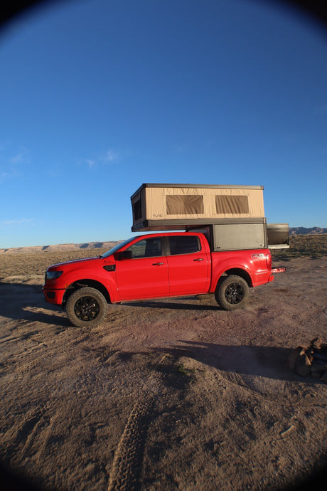 Red Ford Ranger truck with a pop-up camper ready for desert adventures. Consider this versatile RV rental option.