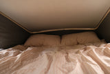 Cozy RV rental bed with striped bedding inside a pop-top camper. Ideal for comfortable rest on your travels.