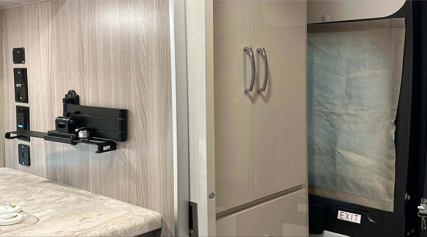  plus a peek at the bathroom.|A built-in stainless steel mini-fridge under a light-colored counter in an RV rental