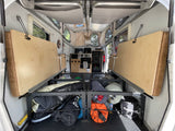 Interior of an rv rental pop-up camper. Beds are lifted, revealing under-bed storage packed with camping gear, alongside a compact kitchen.