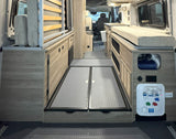 RV rental interior: A compact camper van setup with versatile storage, convertible bed, and water utility panel.
