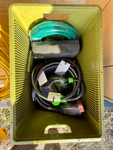 RV rental ready: A green crate holds essential RV accessories, including a power cord with surge protector, and a water hose.