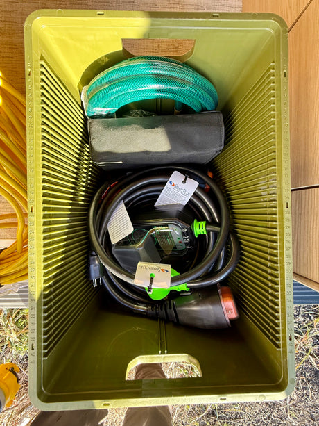 RV rental ready: A green crate holds essential RV accessories, including a power cord with surge protector, and a water hose.