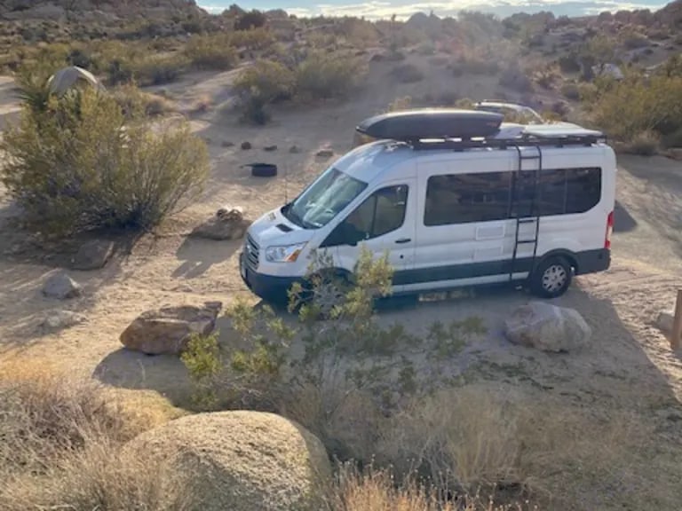 White camper van RV rental parked in a sunny, rocky desert landscape with sparse bushes. Ideal for adventure. — photo 8