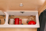 RV rental kitchen amenities: Open overhead cabinet holds a red tea kettle, coffee press, and mug for travel.