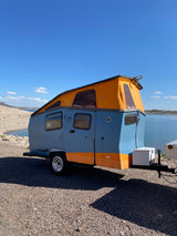 Lakeside RV rental: a stylish blue Cricket camper with an orange pop-top tent, perfect for outdoor adventures.
