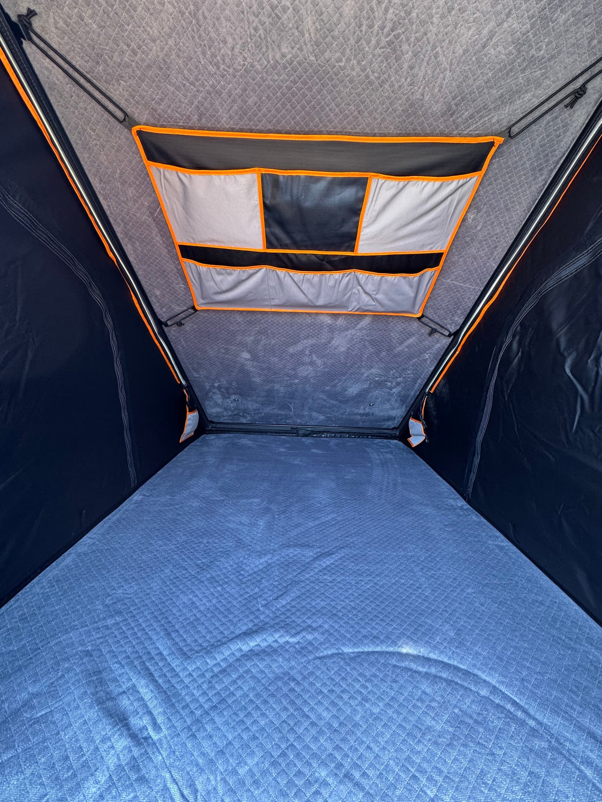 RV rental: Inside a comfortable rooftop tent, featuring a quilted blue mattress and overhead storage pockets. — photo 12