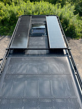 Overhead view of an RV rental rooftop featuring solar panels, a central vent, and a perforated cargo deck.