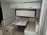 RV rental dinette area featuring comfortable benches, a patterned table, and overhead cabinets, ideal for meals or work.