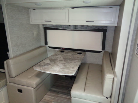 RV rental dinette area featuring comfortable benches, a patterned table, and overhead cabinets, ideal for meals or work.