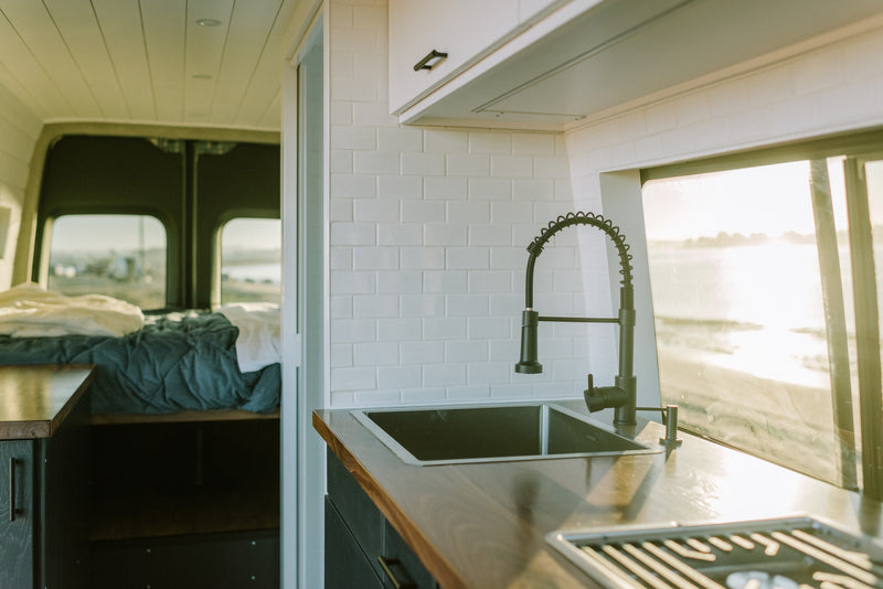 Stylish RV rental interior: cozy camper van with a kitchen, comfortable bed, and scenic waterfront views. — photo 7