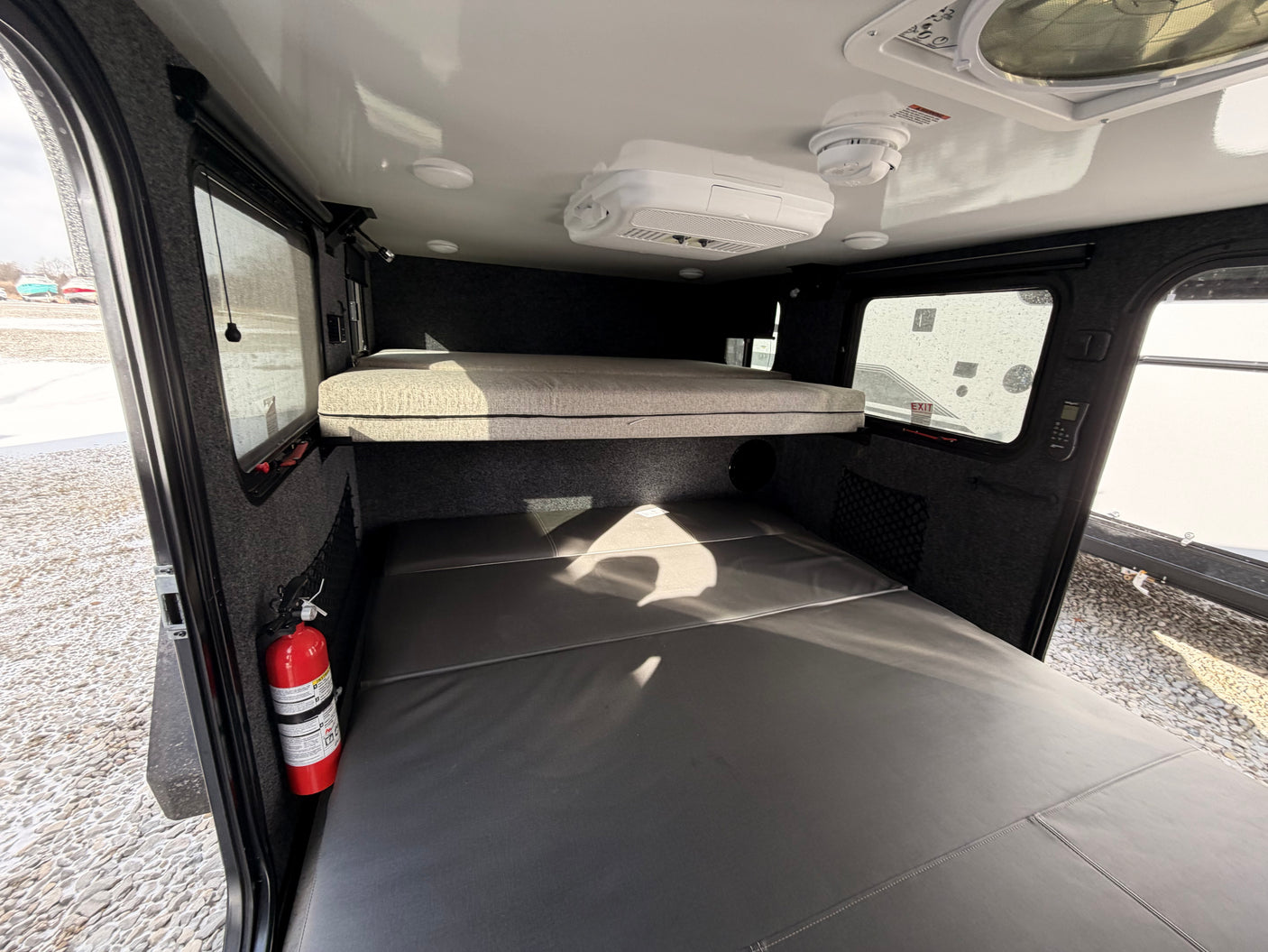 Cozy rv rental interior with bunk beds, AC, smoke detector, and a fire extinguisher, ensuring comfort and safety.