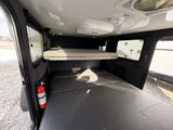 Cozy rv rental interior with bunk beds, AC, smoke detector, and a fire extinguisher, ensuring comfort and safety.