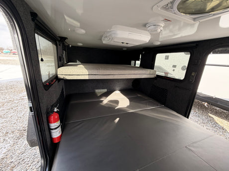 Cozy rv rental interior with bunk beds, AC, smoke detector, and a fire extinguisher, ensuring comfort and safety.