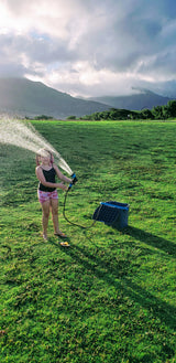 Scenic mountain view as a girl sprays water in a field. Imagine this fun during your next RV rental trip!