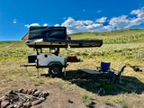 Rugged off-road overland trailer with rooftop tent setup for remote camping. Explore with this unique RV rental.