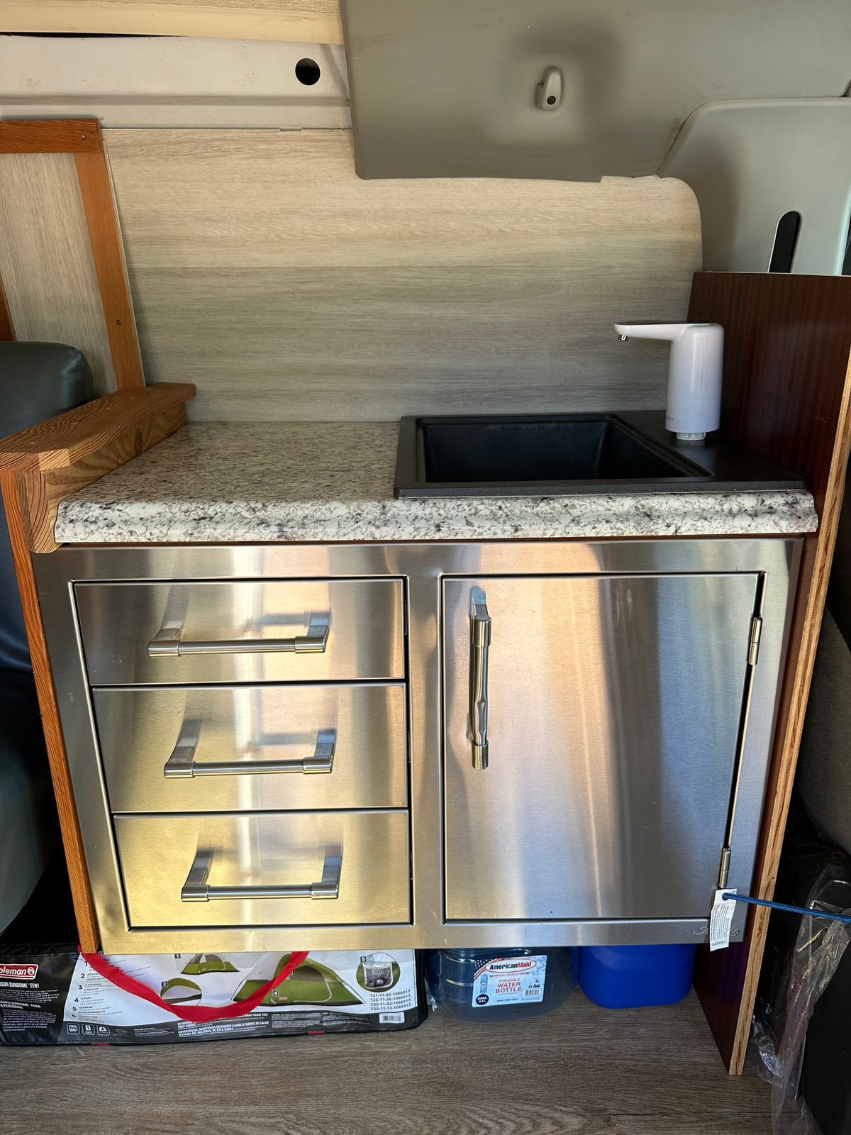 RV rental kitchenette with sink, electric faucet, granite counter, and stainless steel storage drawers. — photo 11