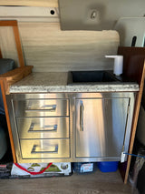 RV rental kitchenette with sink, electric faucet, granite counter, and stainless steel storage drawers.