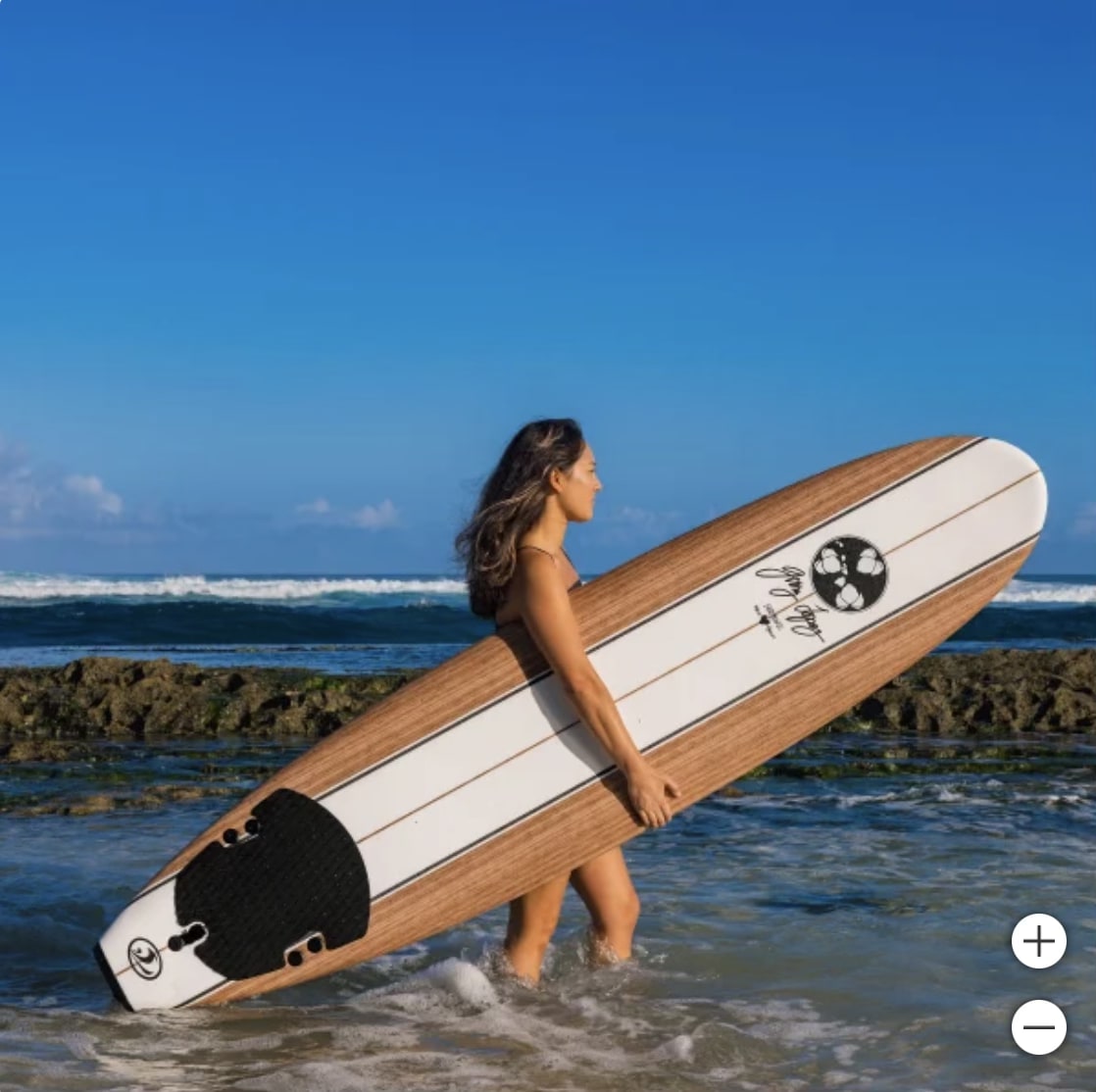 A woman with long hair stands in the ocean, holding a wooden surfboard. This serene coastal adventure is perfect after an RV rental journey. — photo 16