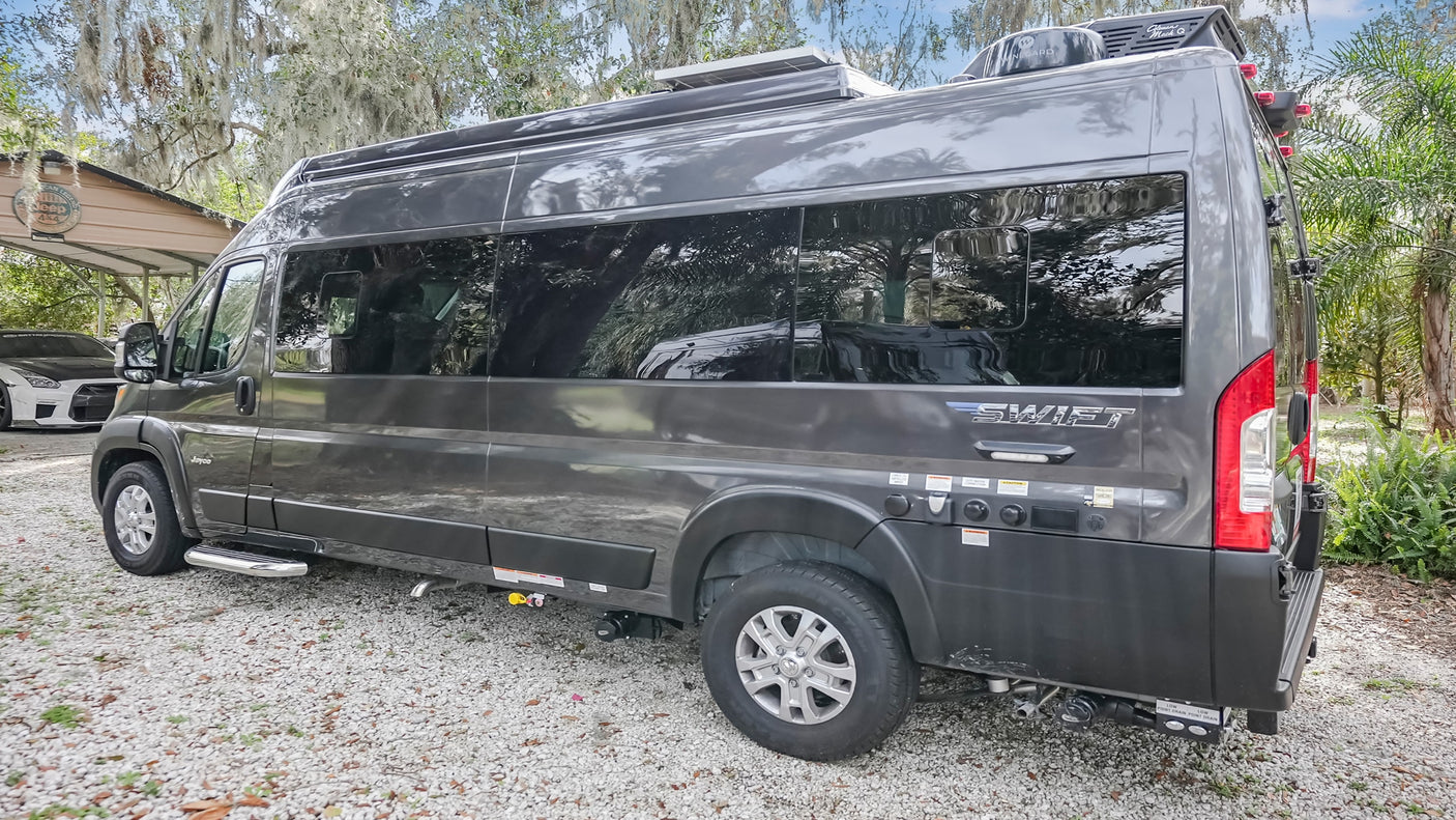 Gray Jayco Swift campervan parked on gravel. Ideal for RV rental, offering adventure travel. Features solar & utility access.