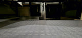 RV rental: Textured floor leads to organized storage under the bed in a camper van, showing hidden compartments.