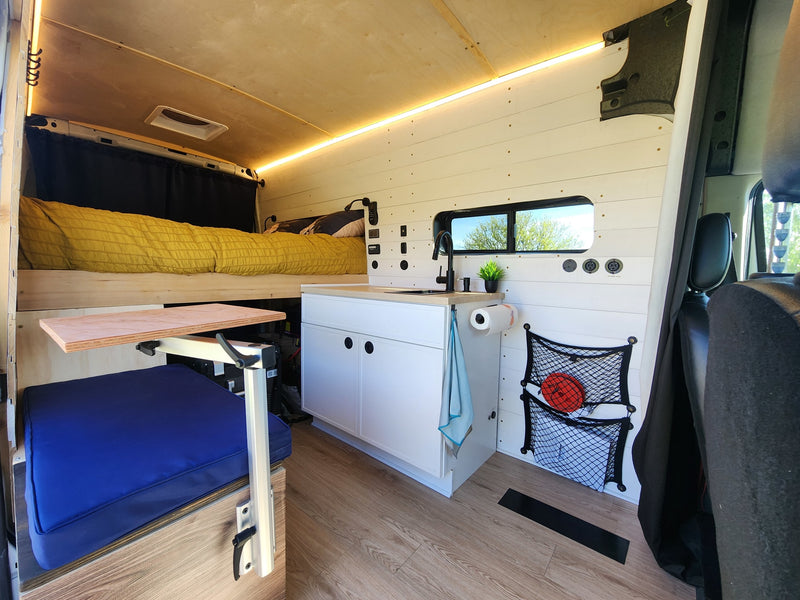 Spacious rv rental with a bright interior, raised bed, kitchenette, and flexible dining area, perfect for road trips. — photo 4