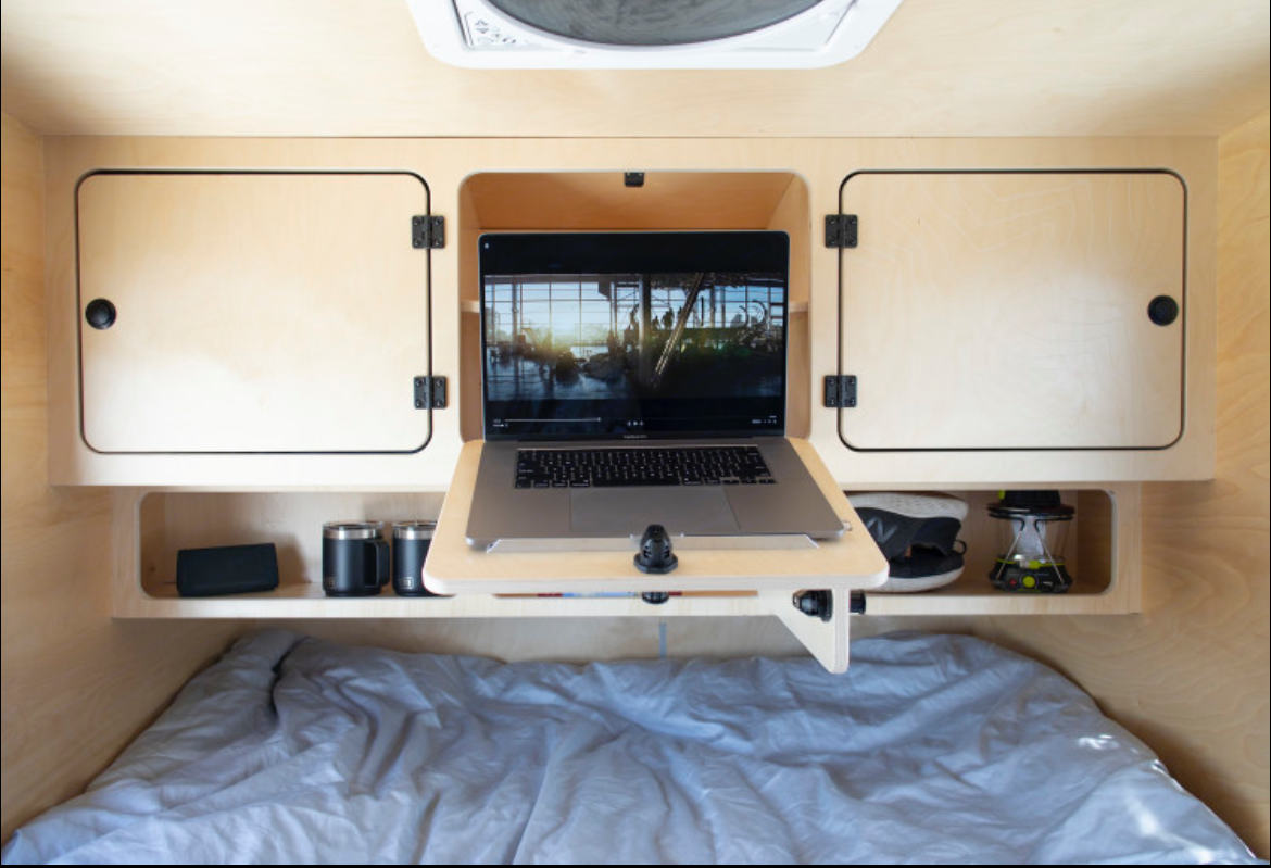 Cozy RV rental bedroom features a built-in laptop desk, ample storage, and a comfy bed for digital nomads.