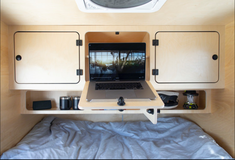 Cozy RV rental bedroom features a built-in laptop desk, ample storage, and a comfy bed for digital nomads.