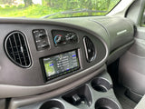 Dashboard of an RV rental van with a modern Kenwood radio, climate controls, and cupholders, ready for travel.