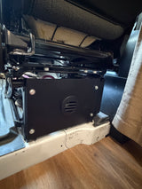 RV rental: Under-seat black box enclosure with a vent, installed beneath a vehicle seat, providing interior storage.