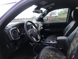 Toyota Tacoma interior. Patterned seats, dashboard, and view of a white vehicle resembling an RV rental outside.