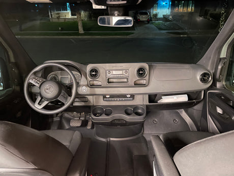 Nighttime view from an RV rental, showing the Mercedes-Benz Sprinter's dashboard, steering wheel, and street outside.