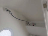 Compact shower and basin in an RV rental bathroom, featuring a flexible shower head and a round window.
