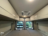 Spacious RV rental interior with overhead storage, comfortable bed, AC, and scenic back windows. Ideal camper van travel.
