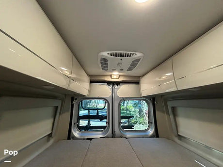 Spacious RV rental interior with overhead storage, comfortable bed, AC, and scenic back windows. Ideal camper van travel.