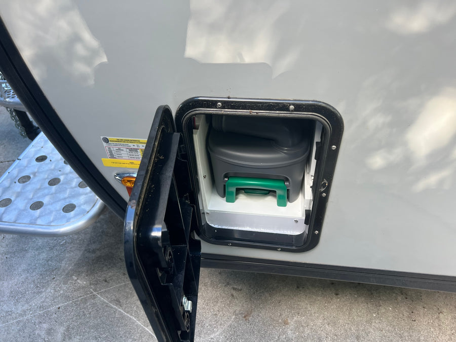 RV rental: Open side compartment shows the removable waste cassette of the portable toilet, essential for camping.