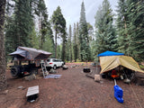 Spacious forest campsite featuring a rooftop tent trailer & ground tent setup. An ideal RV rental alternative for adventure!