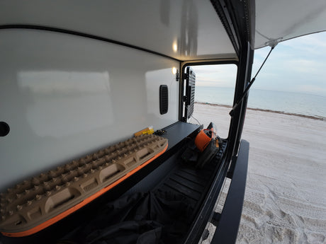 Inside an RV rental's side storage: recovery boards, tools & bags. Perfect for beachside overlanding adventures!