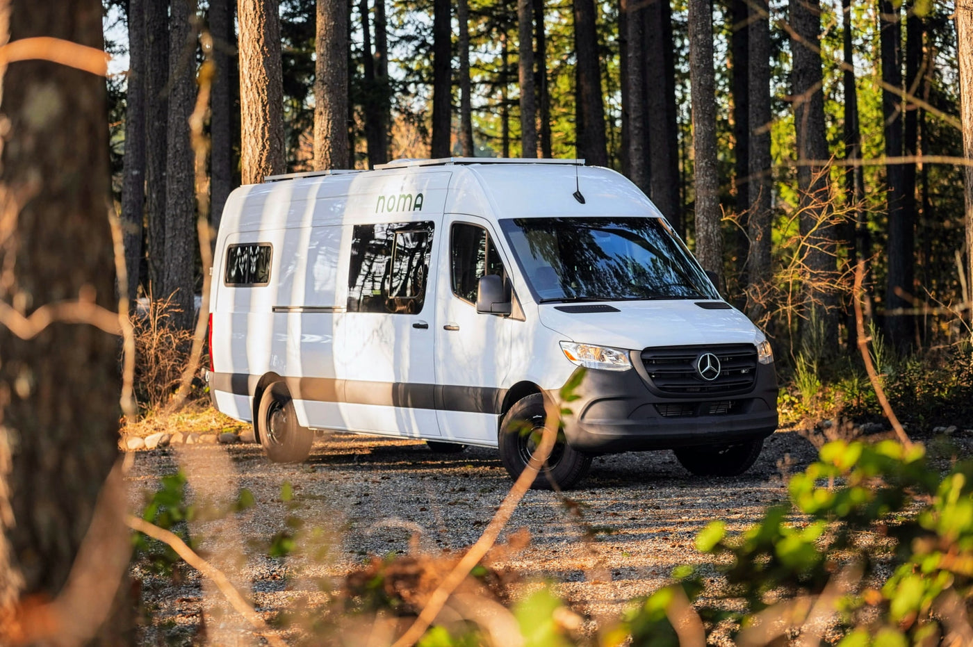 White Mercedes Sprinter camper van (Noma RV rental) parked in a sun-drenched forest. Perfect for adventures. — photo 16