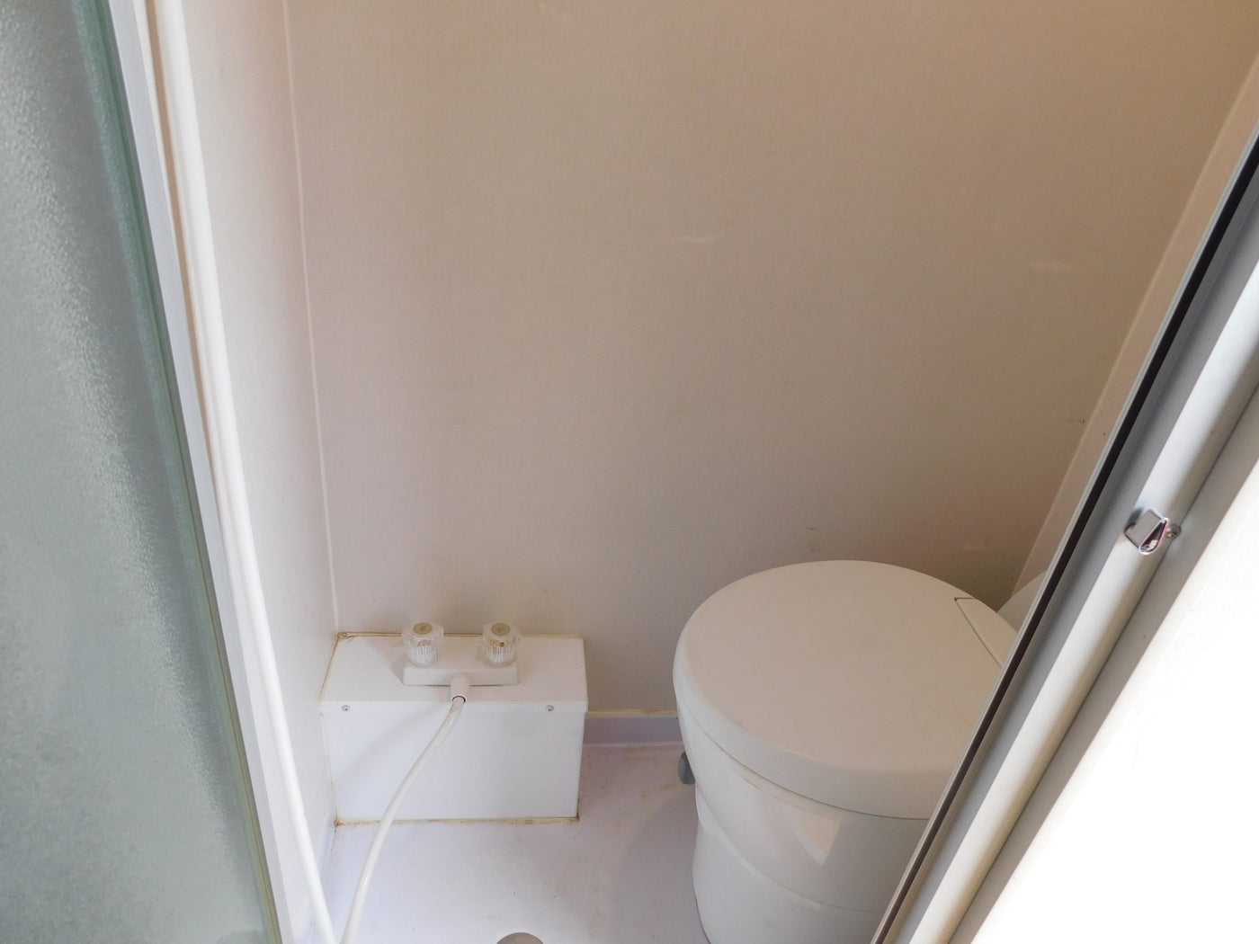 RV rental bathroom with compact shower area (controls & hose) and a round, self-contained toilet. — photo 6
