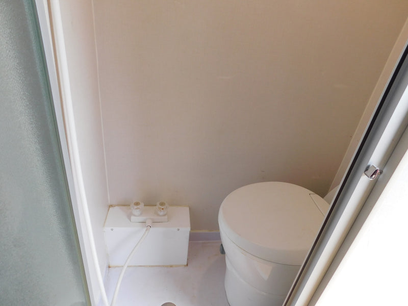 RV rental bathroom with compact shower area (controls & hose) and a round, self-contained toilet. — photo 6